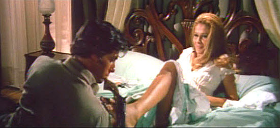 Ida Galli as Belle Boyd presents Robert Woods as Cap. Chris Tanner with the six-gun he hid in her bed in Machine Gun Killers (1968)