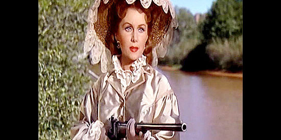 Rhonda Fleming as Madeline Danzeeger, greeting two passers-by at the point of a rifle in The Eagle and the Hawk (1950)