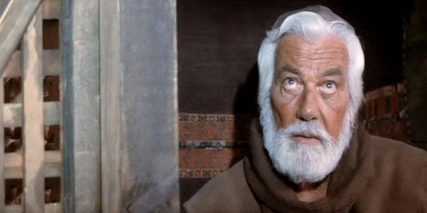Cesar Romero as the long-suffering Father Garcia, listening to Abel Wood's first confession in decades in Lust in the Dust (1985)