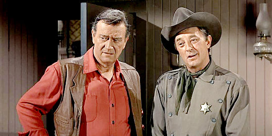 John Wayne as Cole Thornton and Robert Mitchum as J.P. Harrash, contemplating their shared interest in Maudie in El Dorado (1967)