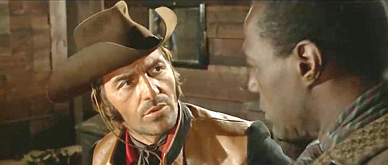Tony Kendall as Santana and Ray Saunders as Thomas discuss Jessica’s plight in Gunman of 100 Crosses (1971)