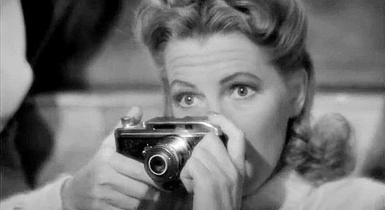 Jean Arthur as Molly J. Truesdale, about to snap a photo that takes her vacation on an unexpected detour in A Lady Takes a Chance (1943)