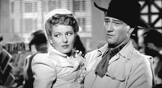 Jean Arthur as Molly J. Truesdale finds herself in the arms of a cowboy named Duke Hudkins (John Wayne) in A Lady Takes a Chance (1943)