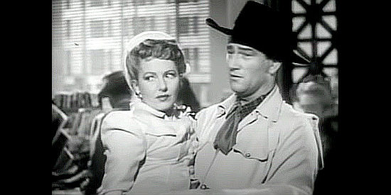 Jean Arthur as Molly J. Truesdale finds herself in the arms of a cowboy named Duke Hudkins (John Wayne) in A Lady Takes a Chance (1943)