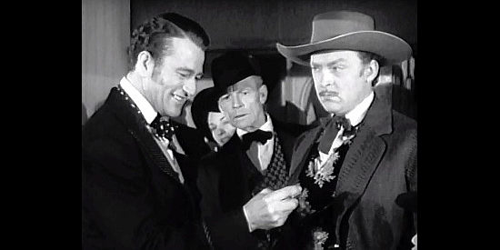 John Wayne as Tom Craig shows off his strength by bending a coin while Brit Dawson (Albert Dekker) looks on in In Old California (1942)