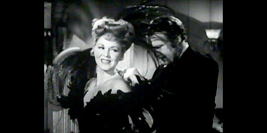 Albert Dekker as Bat Masterson works around feathers to help Dora Hand (Claire Trevor) change in The Woman of the Town (1943)