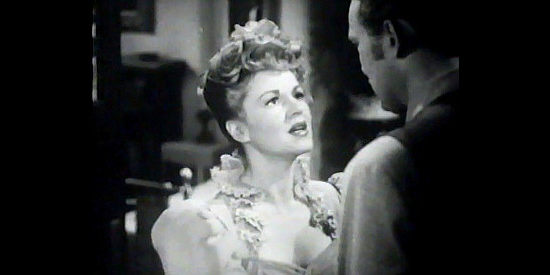 Claire Trevor as Dora Hand, a saloon singer worried about the safety of the man she loves in The Woman of the Town (1943)