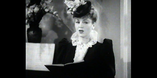 Claire Trevor as Dora Hand, trying her hand singing in a church in The Woman of the Town (1943)