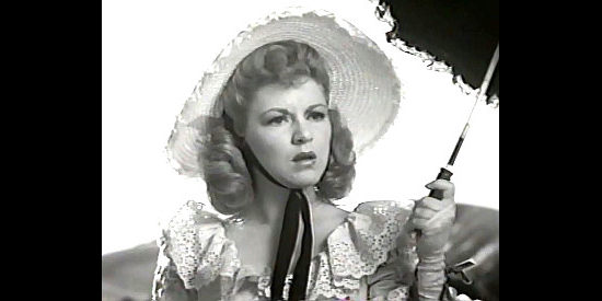 Claire Trevor as Mike King, startled when a stranger shows up demanding one of the horses pulling her buckboard in Texas (1941)
