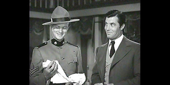 William Lundigan as Jim Gardiner, admiring a scarf that appears to clear Blackie Marshall (James Craig) in Northwest Rangers (1942)