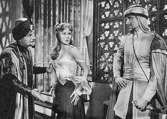 Rhonda Fleming as Roxana Reil is introduced to Omar Id-Din (Rex Reason) as a possible addition to his harem in Yankee Pasha (1954)
