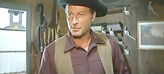 Lex Baker as Sam Dobie, making a business proposition to gunshop owner Cathy Carmichael in Who Killed Johnny R. (1966)