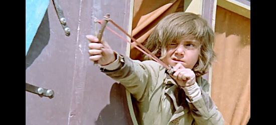 Iker Inanoglu as Yumurcak, taking aim with his trusty slingshot as bandits approach in The Little Cowboy (1973)
