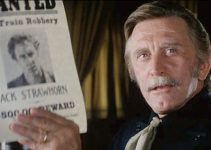 Kirk Douglas as Howard Nightingale, holding the wanted poster of the man he wants to capture most in Posse (1975)