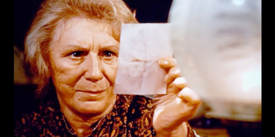 Judith Anderson as Caroline Straulle, checking out a photo of a missing man in Inn of the Damned (1975)