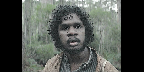 Baykali Ganambarr as Billy Mangana, realizing Claire isn't seeking a lost husband in The Nightingale (2018)