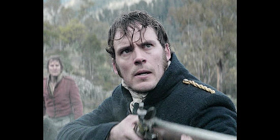 Sam Claflin as Lt. Hawkins, taking aim at a pursuer in The Nightingale (2018)