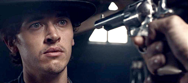 Tom Blyth as William H. Bonney, under a bounty man's pistol in Billy the Kid (2022)