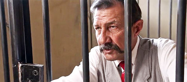 John Marrs as Sheriff Danberry, finding himself locked in one of his own jail cells in Promise (2021)