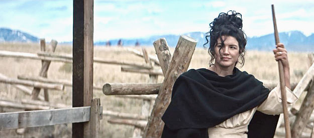 Gina Carano as Hattie McAllister, working on the homestead as riders appear on the horizon in Terror on the Prairie (2022)