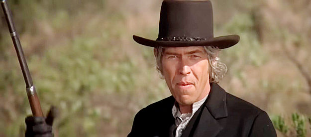 James Coburn as Pat Garrett, eyes pinned on the cabin where Billy is pinned down in Pat Garrett and Billy the Kid (1973)