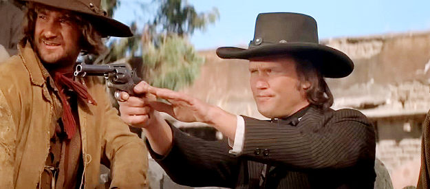 Kris Kristoffersonn as Billy the Kid takes aim at the head of a roster while ---- looks on in Pat Garrett and Billy the Kid (1973)