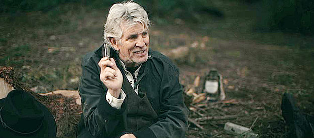 Eric Roberts as Bloody Tom Higgins, showing off a harmonica he took off of one of his victims in The Outlaws (2023)