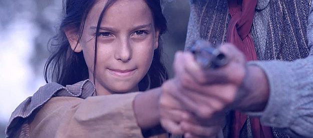 Sofia Ferrera as young Clare, being taught how to handle a pistol in a flashback scene in The Dutchman (2020)