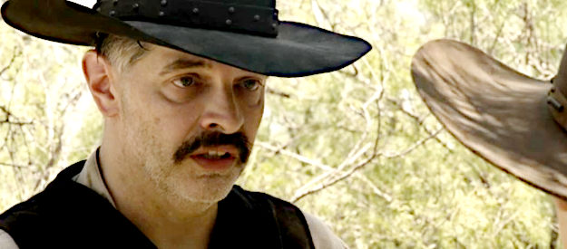 Christopher Henry as George Newcomb, offering Dunn advise on how to stay out of trouble in Lady Outlaw (2024)