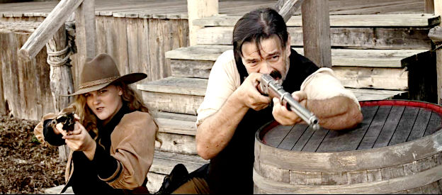 Lisa Butala as Rose Dunn and Christopher Henry as George 'Bittercreek' Newcomb, trying to shoot their way out of a tight spot in Lady Outlaw (2024)