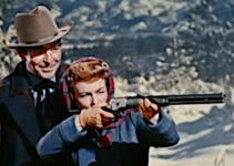 Rod Cameron as Kyle Ramlo, teaching Christine (Ruth Hussey) how to fire a rifle in Woman of the North Country (1952)