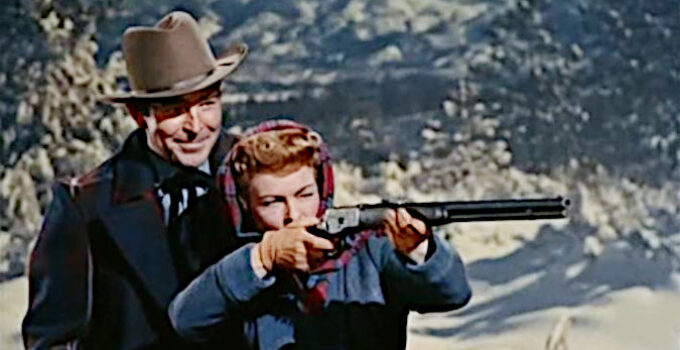 Rod Cameron as Kyle Ramlo, teaching Christine (Ruth Hussey) how to fire a rifle in Woman of the North Country (1952)