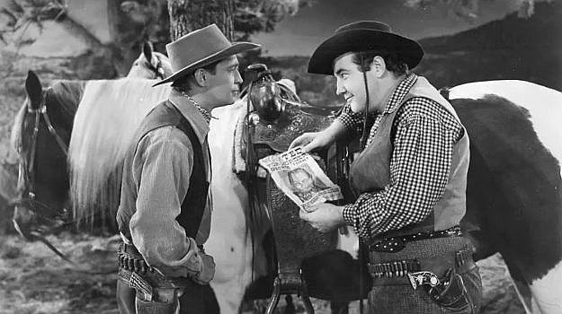 Franchot Tone as Tim 'Kansas' Mason showing Swanee (Broderick Crawford) a wanted poster to help prove his point in Trail of the Vigilantes (1940)