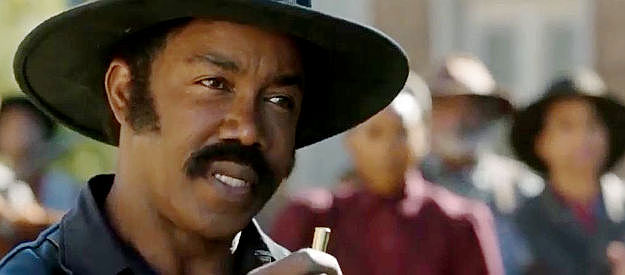 Michael Jai White as Johnny Black, displaying the bullet that bears Brett Clayton's name in Outlaw Johnny Black (2023)