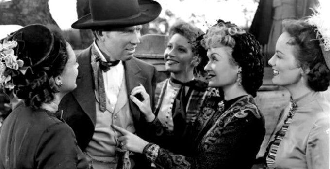 Bruce Cabot as Wild Bill Hickok, surrounded by grateful ladies, incluidng Constance Bennett as Belle Andrews, after stopping a runaway buckboard in Wild Bill Hickok Rides (1942)