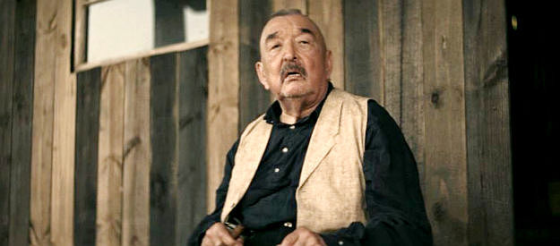 Graham Greene as Hoko, a trading post owner about to be questioned by Col. Dav is's men in Trail of Vengeance (2025)