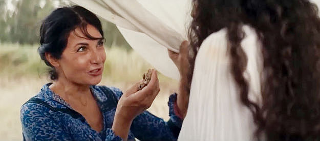 Nadia Bengali as a robbery victim, showing her daughter the money Django has given the family in Django Undisputed (2025)