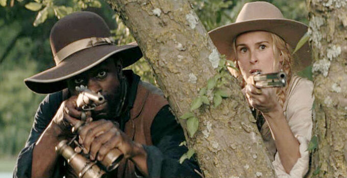 Gbenga Akinnagve as John Scobell and Rumer Willis as Katherine Atherton, approaching Col. Davis's homes in Trail of Vengeance (2025)