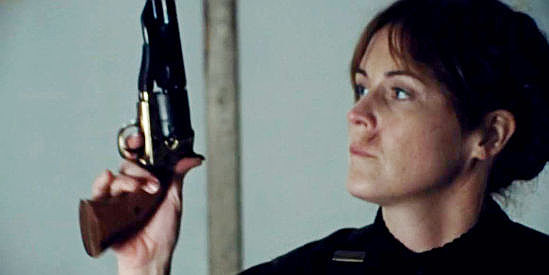 Sheri Rippel as Molly Pray, admiring her late husband's pistol as she prepares for vengeance in They Call Her Death (2025)