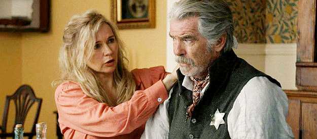 Veronica Ferres as Sarah Dove, treating her wounded husband (Pierce Brosnan) in The Unholy Trinity (2024)
