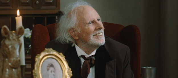 Bruce Dern as railroad tycoon George Wells, beaming in delight at a pretty secretary in Bad Men Must Bleed (2025)