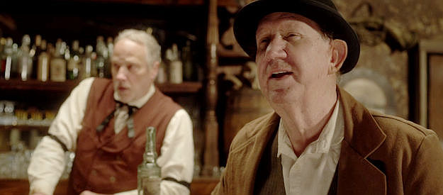 Denny Nolan as town drunk Henry Middleton with saloon owner Earle (Dave Schecter) looking on in Night of the Tommyknockers (2022)