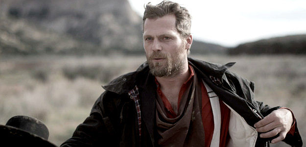 Andrew Key as Prescott 'Mitch' Mitchell, leader of the outlaw gang that stumbles upon the Ballard party in This Bloody Country (2025)