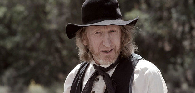 Larry Cedar as Josiah Ballard, a man used to ruling his family and his three wives with an iron fist in This Bloody Country (2025)