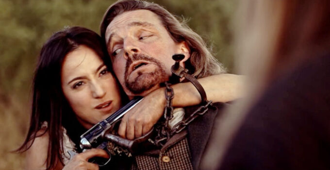 Celeste Luccitti as Bessie, holding a gun on a bounty hunter named Wallace (Christopher Beeman) in Blood Totem (2026)