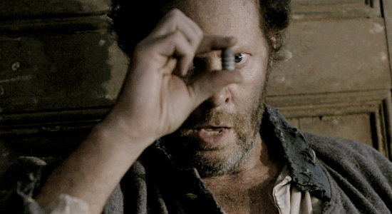 Shuler Hensley as Samuel Barnett examines the bullet dug out of his chest following the Battle of the Wilderness in Marbles and Bullets (2025)